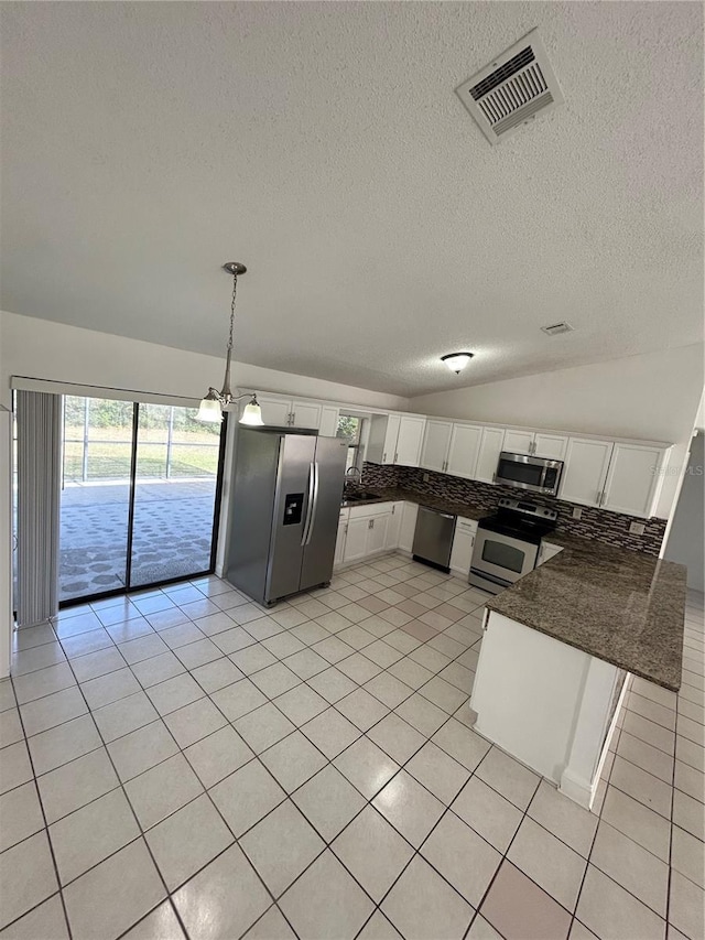 kitchen featuring white cabinetry, lofted ceiling, decorative light fixtures, light tile patterned flooring, and appliances with stainless steel finishes