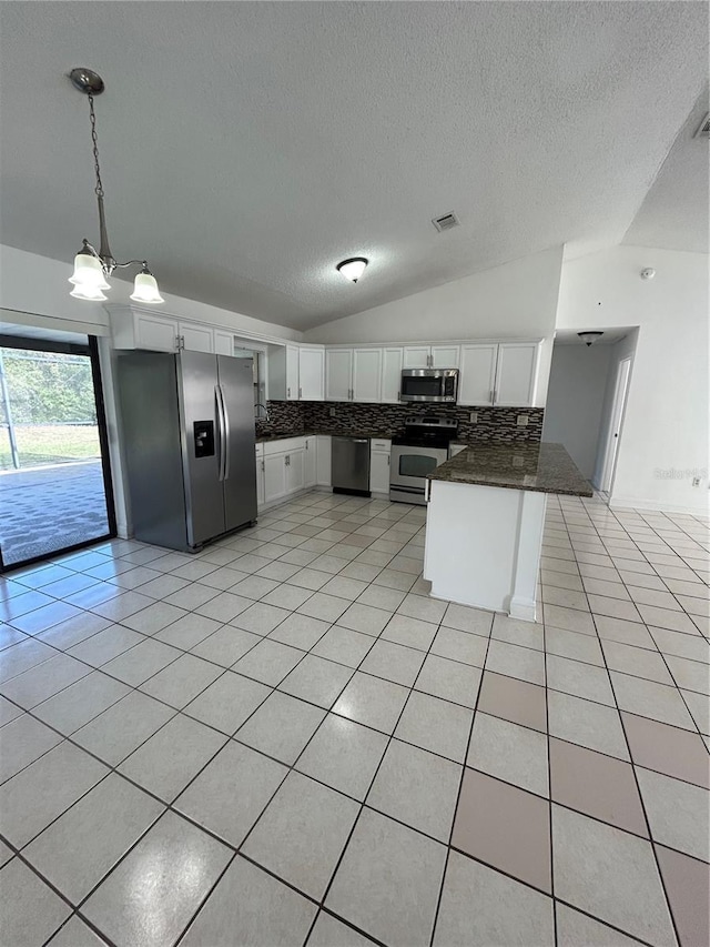 kitchen with lofted ceiling, hanging light fixtures, kitchen peninsula, appliances with stainless steel finishes, and white cabinetry