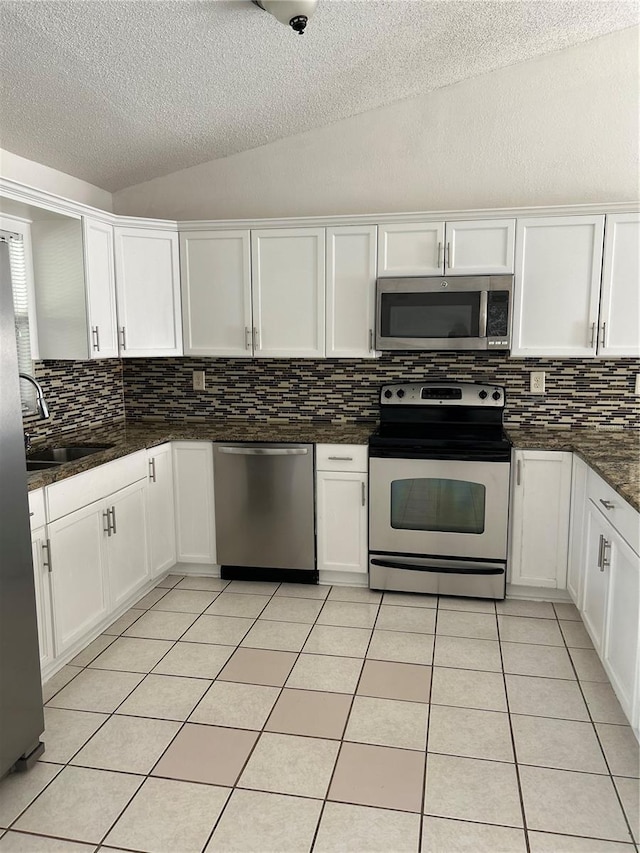 kitchen featuring white cabinetry, lofted ceiling, backsplash, and appliances with stainless steel finishes