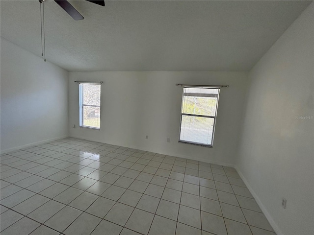 tiled empty room with ceiling fan, a healthy amount of sunlight, lofted ceiling, and a textured ceiling