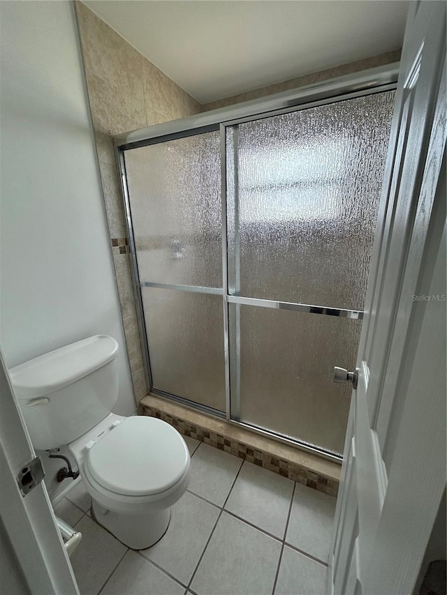 bathroom with tile patterned flooring, toilet, and walk in shower