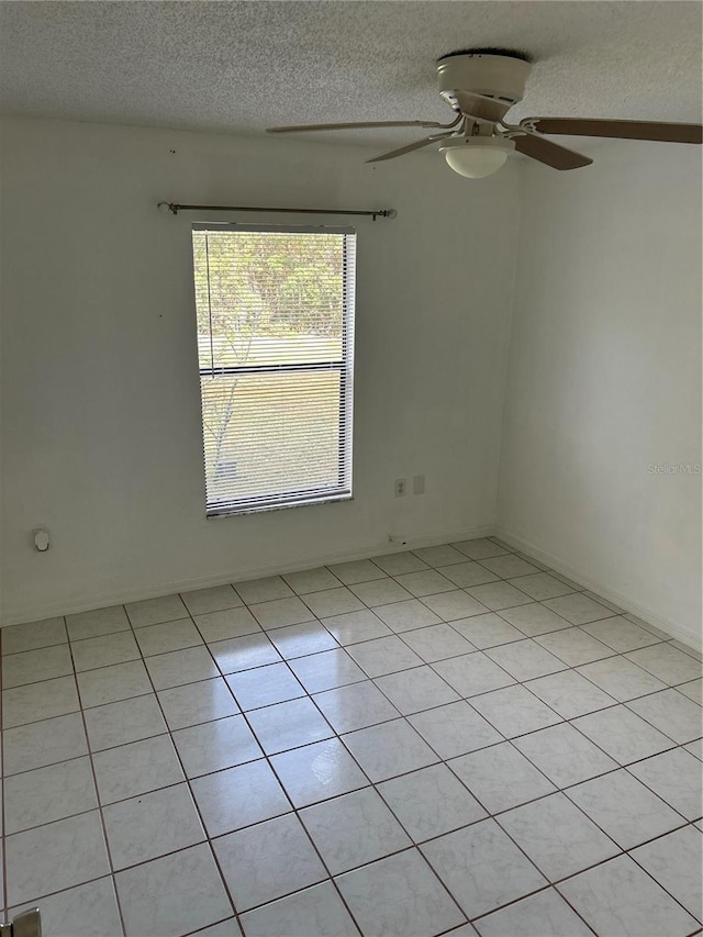 spare room featuring ceiling fan, light tile patterned floors, and a textured ceiling