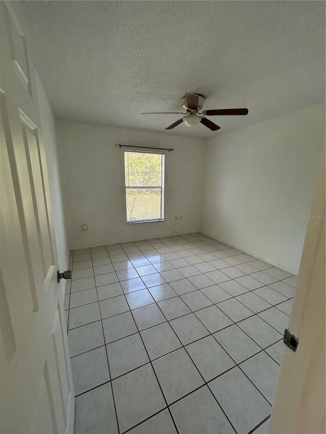 empty room featuring light tile patterned floors, a textured ceiling, and ceiling fan