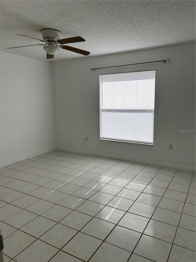 unfurnished room with ceiling fan, light tile patterned flooring, and a textured ceiling