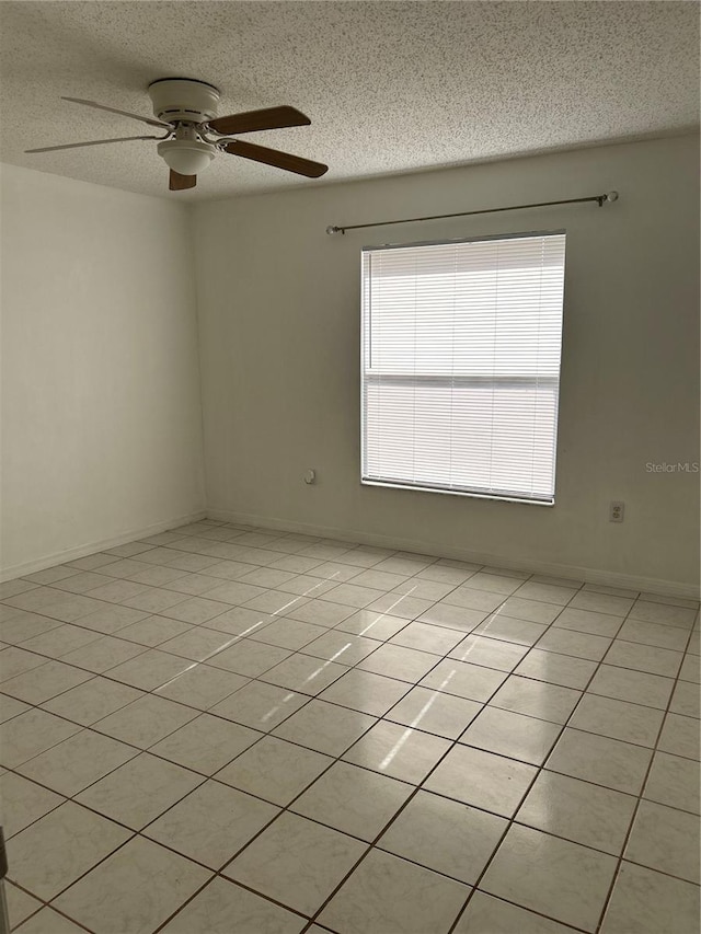 tiled empty room featuring ceiling fan and a textured ceiling