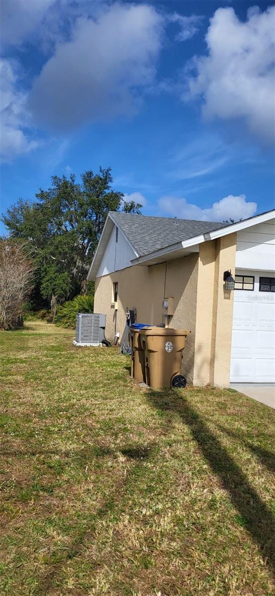 view of side of property with central air condition unit, a yard, and a garage