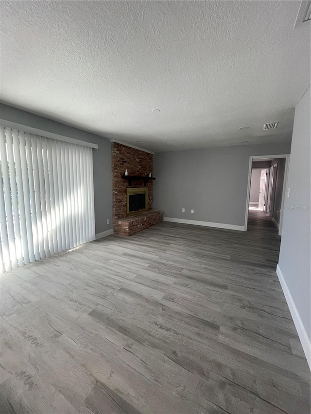 unfurnished living room with a fireplace, a textured ceiling, and hardwood / wood-style flooring