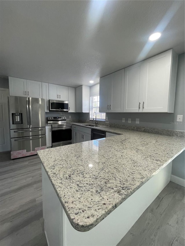 kitchen featuring kitchen peninsula, white cabinetry, and appliances with stainless steel finishes