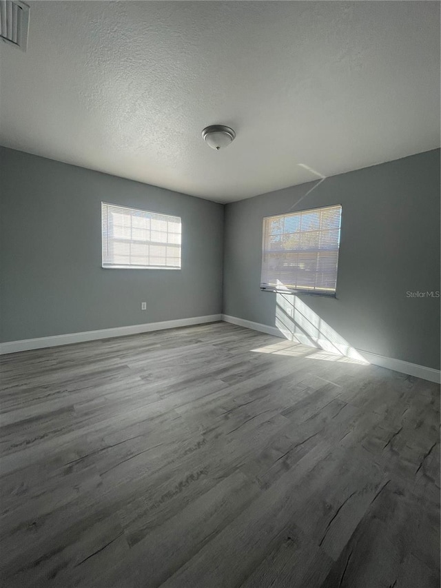 unfurnished room with a healthy amount of sunlight, a textured ceiling, and light wood-type flooring