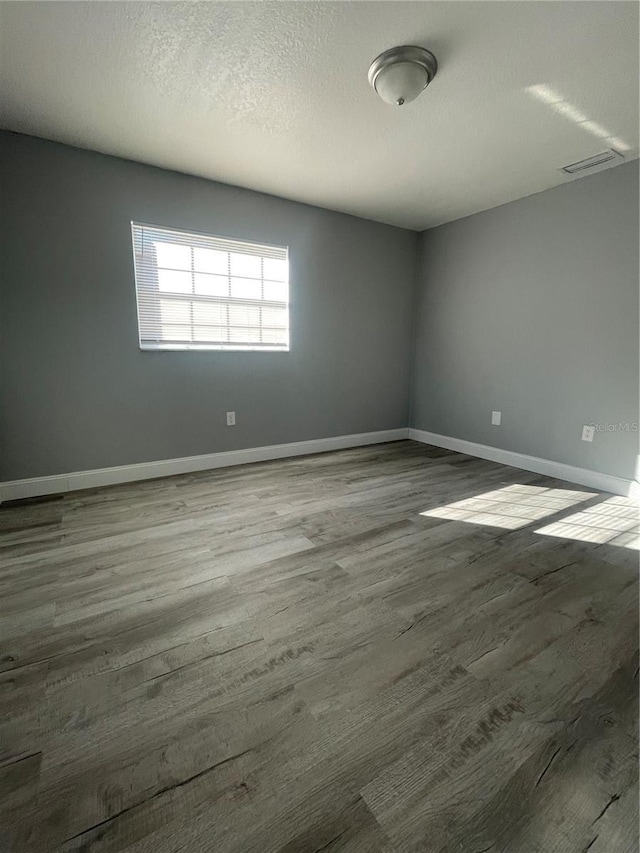 spare room featuring wood-type flooring and a textured ceiling