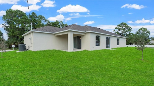 314A Dagama Ct, Kissimmee, FL 34758 - back of property featuring a shingled roof, central air condition unit, stucco siding, and a lawn