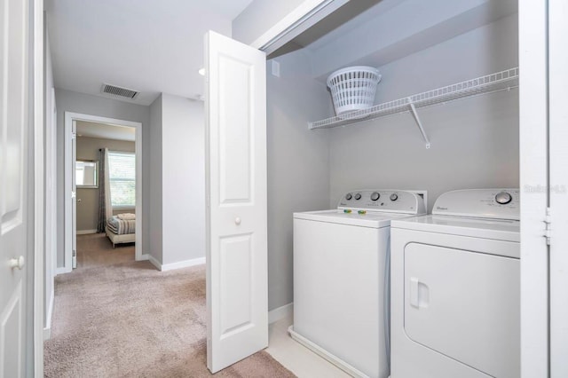 clothes washing area with light carpet and washing machine and clothes dryer