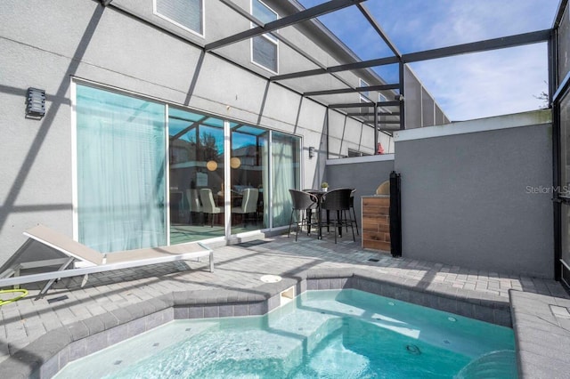 view of pool with a bar, a patio, and a lanai