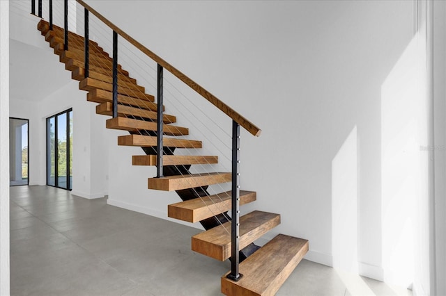 stairs with concrete flooring and a high ceiling