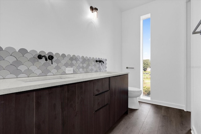 bathroom with wood-type flooring, backsplash, toilet, and sink