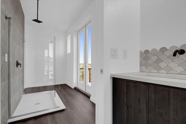 bathroom with decorative backsplash, hardwood / wood-style floors, a shower, and plenty of natural light