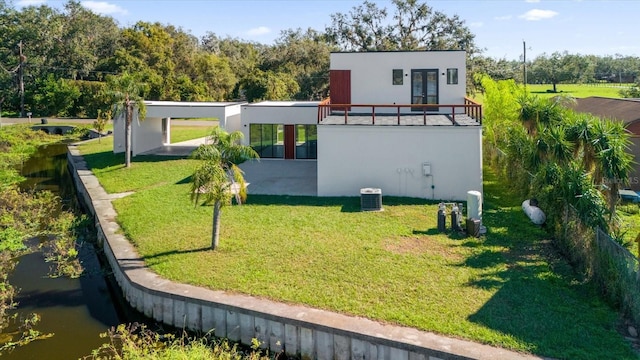 rear view of house featuring a lawn, a patio area, and a balcony