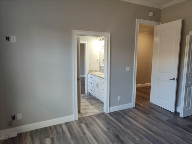 unfurnished bedroom with ensuite bathroom, crown molding, and dark wood-type flooring