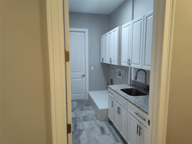 clothes washing area featuring electric dryer hookup, hookup for a washing machine, sink, and cabinets