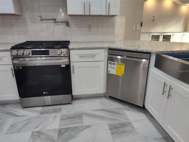 kitchen featuring white cabinets, stainless steel appliances, and light stone counters