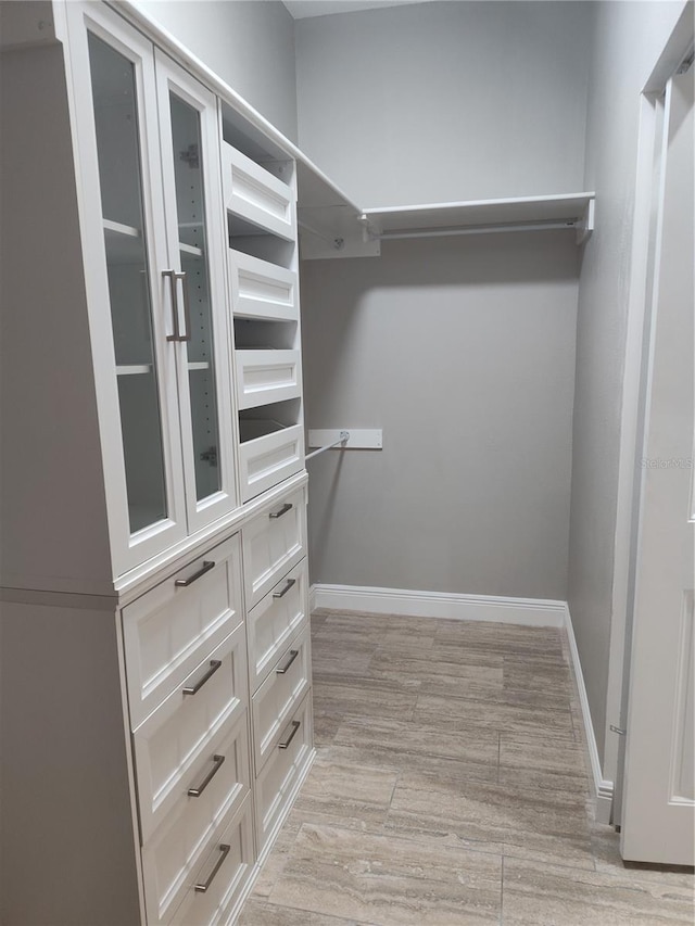 walk in closet with light hardwood / wood-style flooring