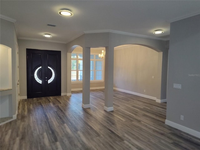 foyer entrance featuring dark wood-type flooring, a notable chandelier, and ornamental molding