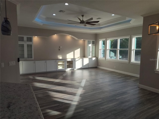 unfurnished room featuring dark hardwood / wood-style floors, ceiling fan, crown molding, and a tray ceiling