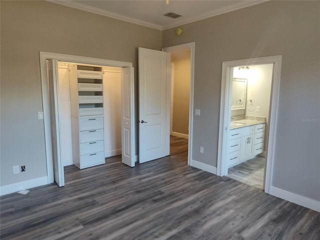 unfurnished bedroom with dark hardwood / wood-style floors, ornamental molding, ensuite bathroom, and a closet