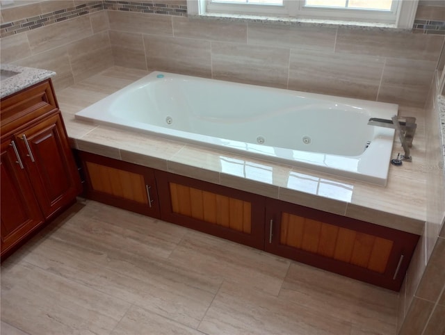 bathroom with vanity and tiled tub