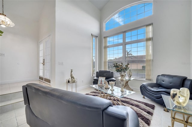 tiled living room featuring a towering ceiling and french doors