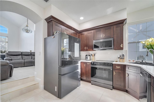 kitchen with decorative backsplash, dark brown cabinetry, stainless steel appliances, sink, and hanging light fixtures