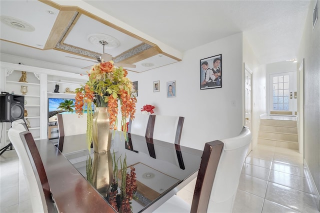 tiled dining room with built in shelves and a raised ceiling