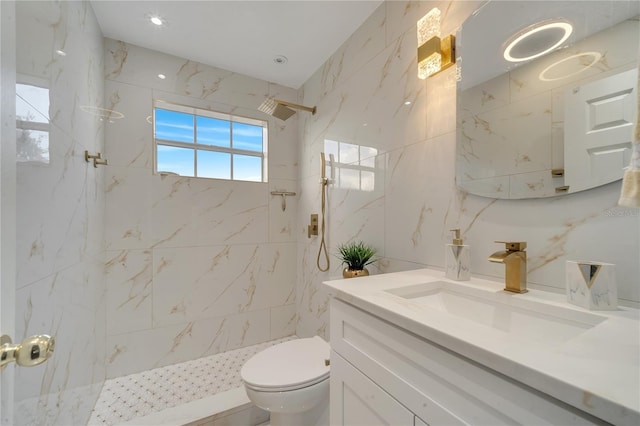 bathroom with tiled shower, vanity, and toilet