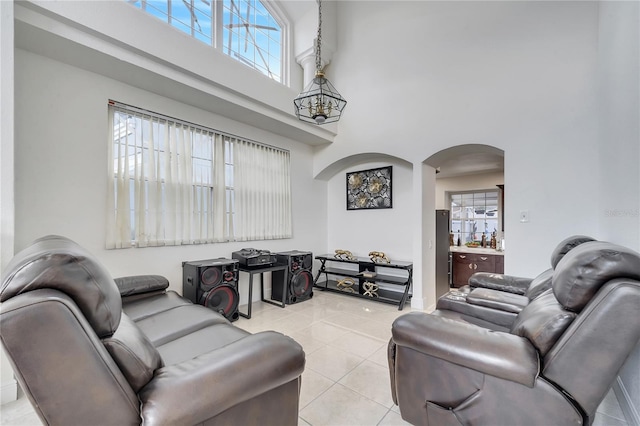 living room featuring light tile patterned flooring, a high ceiling, a wealth of natural light, and a chandelier