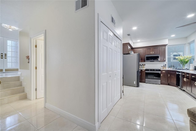 kitchen featuring dark brown cabinets, light tile patterned floors, and stainless steel appliances