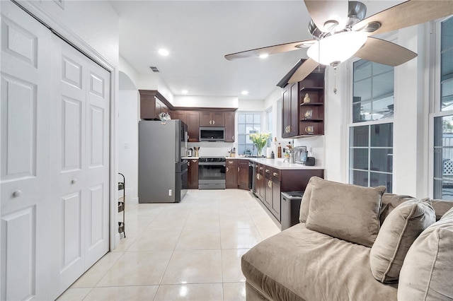 kitchen with dark brown cabinetry, ceiling fan, light tile patterned flooring, and appliances with stainless steel finishes