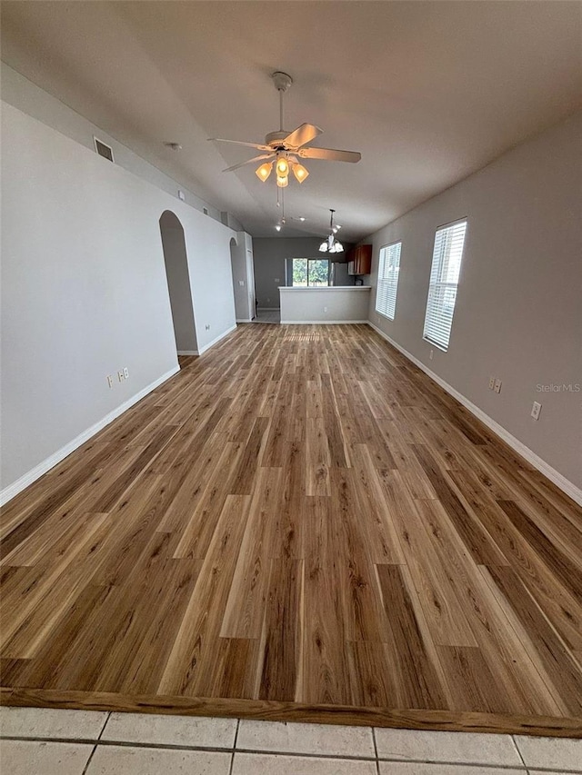 unfurnished living room with hardwood / wood-style floors, ceiling fan, and vaulted ceiling