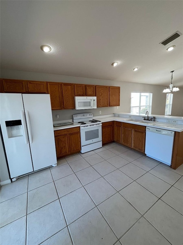 kitchen featuring white appliances, sink, light tile patterned floors, a chandelier, and hanging light fixtures