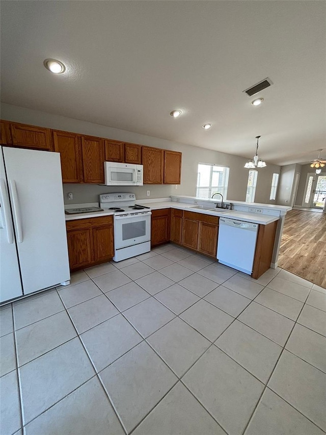 kitchen featuring ceiling fan with notable chandelier, white appliances, sink, pendant lighting, and light hardwood / wood-style floors