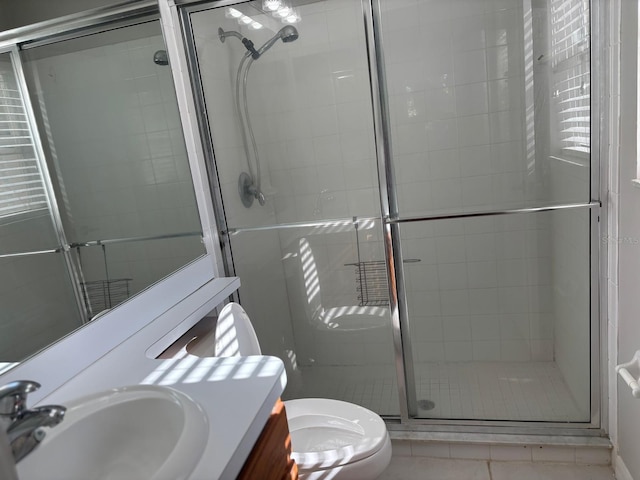 bathroom featuring tile patterned floors, vanity, a shower with shower door, and toilet