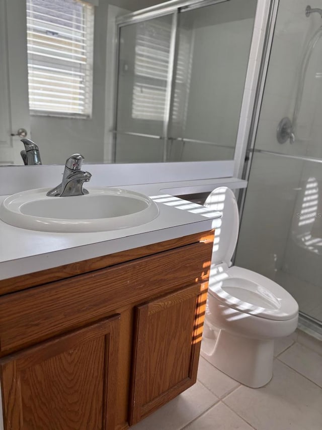 bathroom featuring tile patterned flooring, vanity, toilet, and a shower with shower door