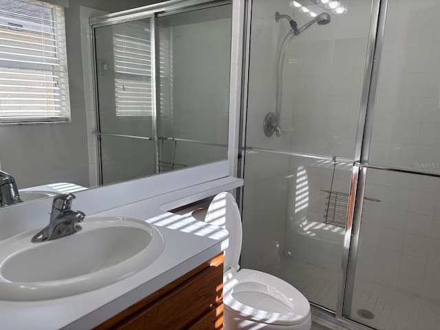 bathroom featuring vanity, toilet, and a shower with shower door