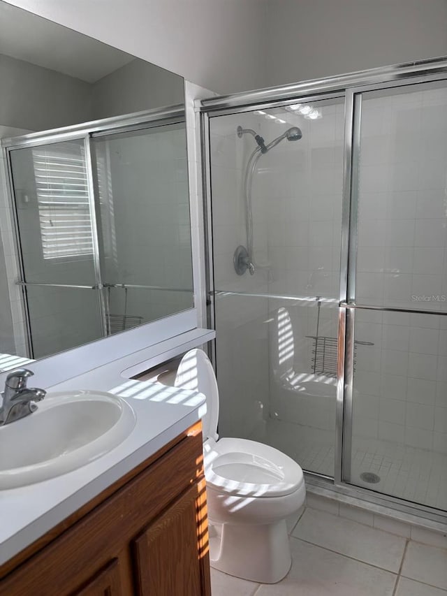 bathroom featuring tile patterned floors, vanity, toilet, and a shower with shower door