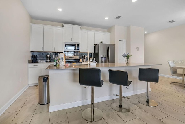 kitchen featuring stainless steel appliances, a center island with sink, and white cabinets