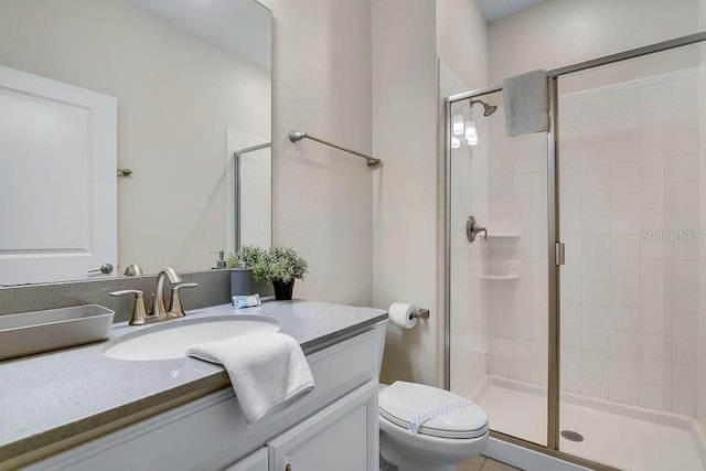 bathroom with vanity, a shower with door, and toilet