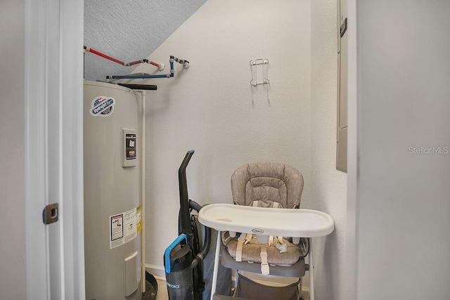 interior space with vaulted ceiling, electric water heater, and a textured ceiling