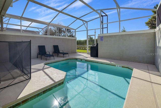 view of pool featuring glass enclosure and a patio area