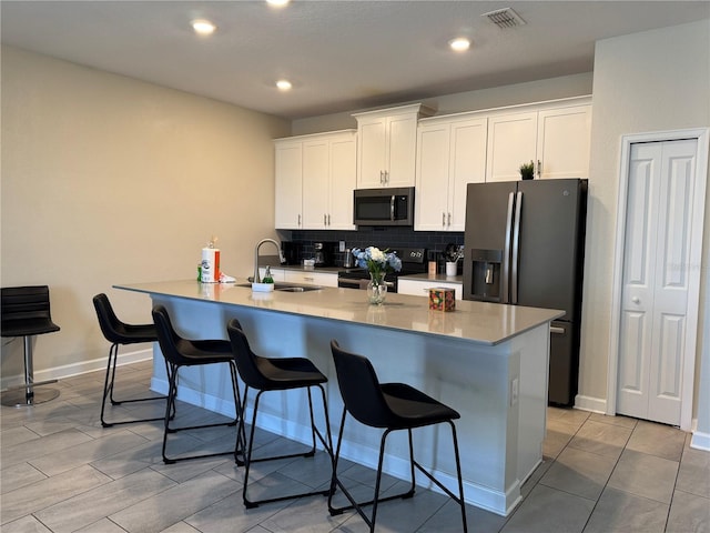kitchen with black / electric stove, fridge with ice dispenser, a sink, stainless steel microwave, and a breakfast bar area