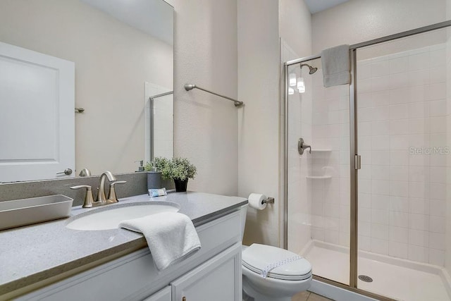 bathroom with vanity, a shower stall, and toilet
