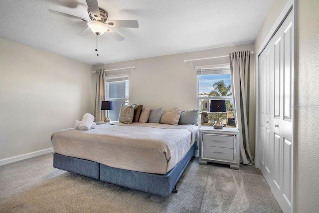 carpeted bedroom featuring a ceiling fan, baseboards, a closet, and multiple windows